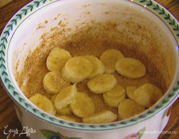 Керамическую форму смазать растительным маслом, присыпать крошкой из печенья (немного оставить), разложить кусочки банана, посыпать 2 ч. ложками сахара.