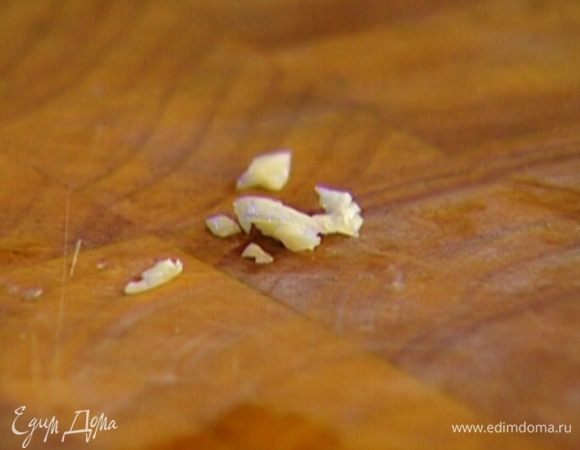 Чеснок почистить, раздавить ножом, удалить сердцевину и мелко нарезать 1/3 зубчика, затем добавить чеснок в заправку и перемешать.