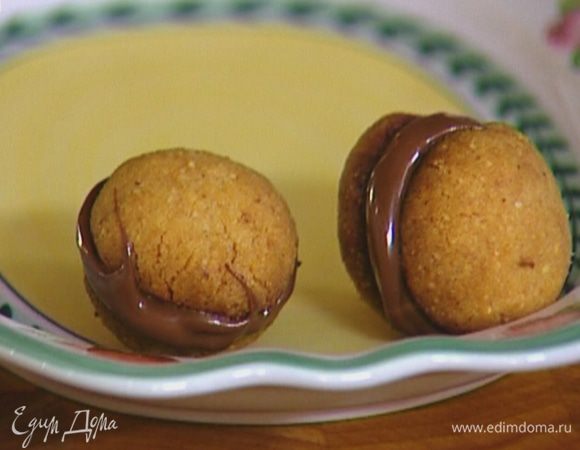 Готовое печенье остудить, смазать плоскую сторону шоколадно-ореховой пастой и соединить каждые две половинки вместе.