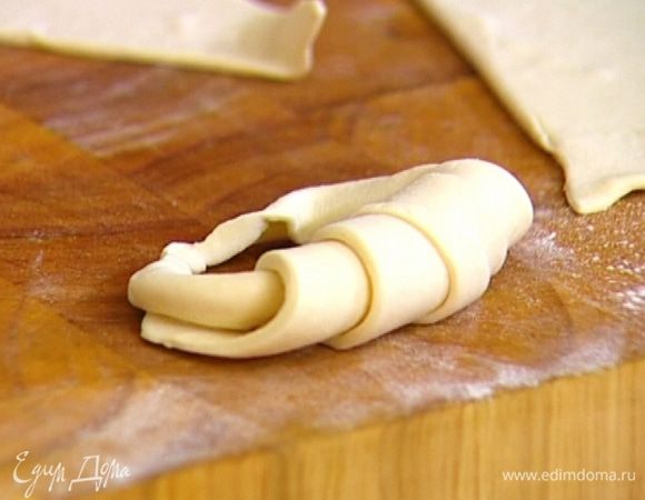 Половину треугольников скатать в рулетики, чтобы завершающим был острый угол. Затем кончики круассана растянуть в стороны и скрепить их, плотно прижав пальцами.