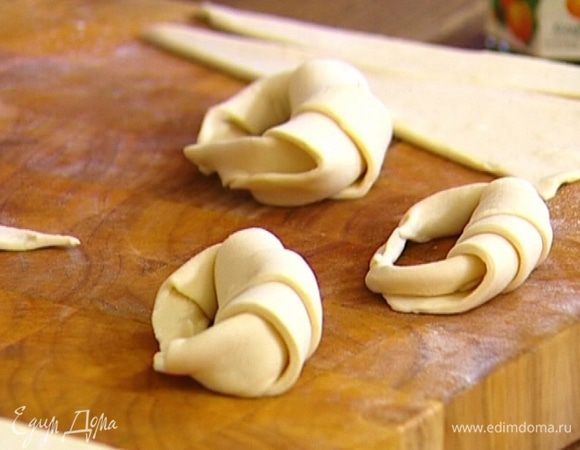 На одну сторону оставшихся треугольников (противоположную острому углу) выложить по 2 ч. ложки конфитюра и скатать в рулетики. Кончики соединить и прижать пальцами.