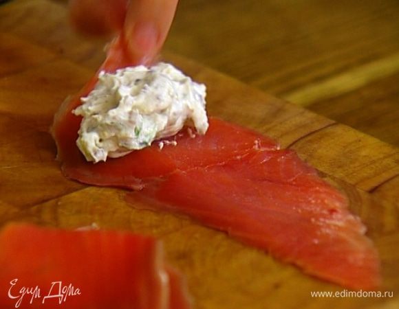 На один край каждого ломтика семги выложить немного творожной начинки, свернуть семгу в рулет и завязать пером лука, чтобы не раскрывался.