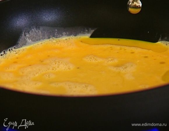 Разогреть в сковороде оливковое масло, вылить в нее яичную массу и готовить на среднем огне.