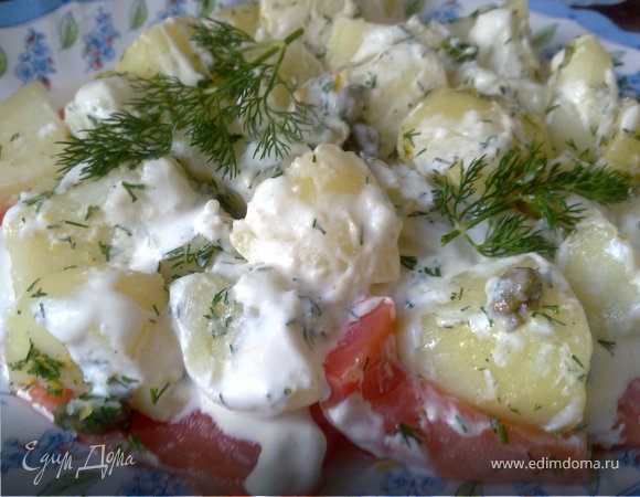 Очистить и отварить картофель целиком (лучше взять молодую некрупную картошку). 
Чтобы в картофеле сохранялись питательные вещества и витамин С нужно не класть ее в холодную воду, а варить в кипящей подсоленной воде. Когда картошка готова, слейте воду. 
Сделаем основную заправку: в глубокой миске смешать цедру лимона - она придаст пикантность и аромат, сок лимона, соль, перец, немного каперсов и оливковое масло в пропорции 3:1 к лимонному соку.
Если картофель мелкий можно оставить его целиком, а картофелины побольше лучше разрезать. Опустить ещё горячий картофель в заправку, хорошо всё перемешать, если нужно - досолить.
Можно добавить немного хорошего уксуса (белого или красного вина) - это придаст картофелю приятный привкус.
Берем копченого лосося (нарезку, или нарезать как можно тоньше), выкладываем на блюдо. Нарезаем укроп и посыпаем им картофель, тщательно перемешиваем и аккуратно выкладываем картофель сверху на лосося горкой.
Теперь добавим сметану (можно использовать творог или йогурт), пару ложек сметаны смешать с соком половинки лимона, натереть в сметану хрен (можно добавить уже готовый), посолить и размешать.
Полить сметанным соусом сверху.
