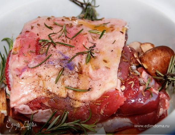 Баранину вымыть ,обсушить.Натереть ее солью,перцем и кумином.Выложить на овощи.Шампиньоны разрезать на четыре части,добавить к мясу.Добавить веточки розмарина.Еще раз сбрызнуть оливковым маслом,накрыть крышкой и дать постоять мин 20.