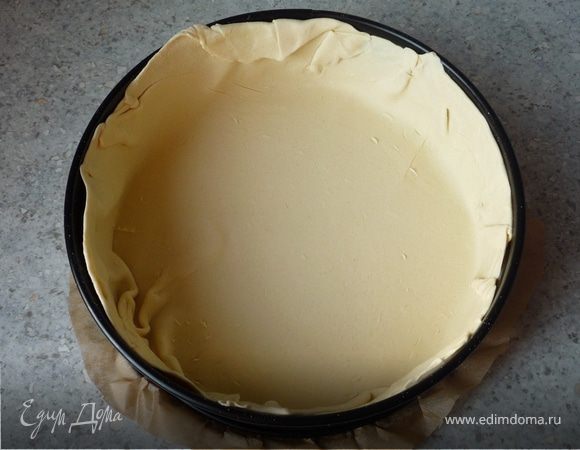 Слоеное тесто разморозить. Картофель отварить в мундире, остудить, почичтить и нарезать пластинками. Перец помыть, почистить и нарезать полосками. Разогреть духовку
до 200°C. 2/3 слоеного теста раскатать и выложить в разъемную форму (24-26см), дно которой покрыто бумагой для запекания. Сформировать бортики. 