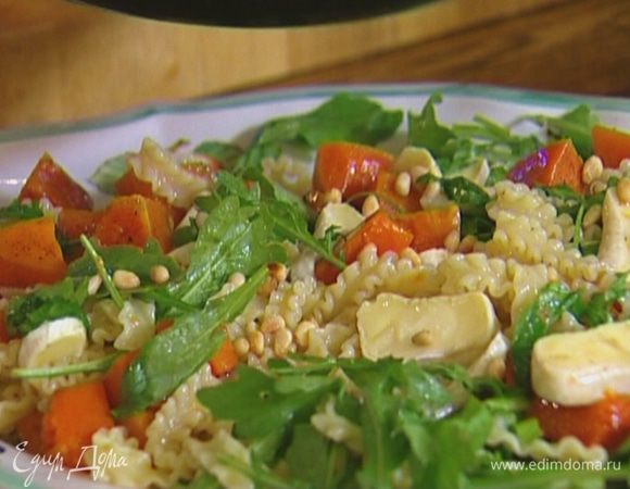 Отправить к макаронам руколу, перемешать, выложить в салатницу, посыпать кедровыми орехами и сбрызнуть оливковым маслом.