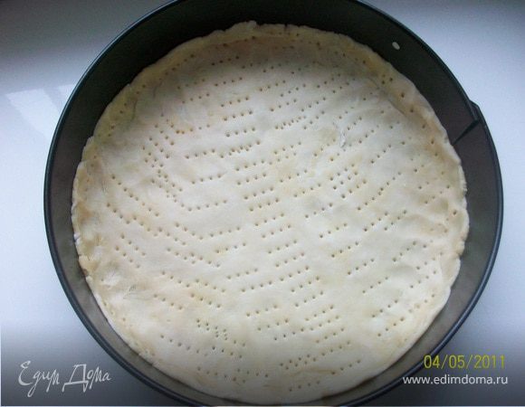 Форму диаметром 23-24 см. смазать сливочным маслом, выложить тесто, сдалать бортики, наколоть вилкой. Я запекла корж без начинки в течении 15 мин. в предварительно разогретой до  180°С духовке, что и вам сделать рекомендую.