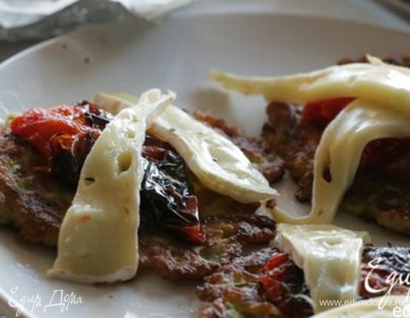 Выстелить противень бумагой для выпечки, выложить готовые оладушки, сверху разложить сыр и помидоры. Отправить на 2−3 минуты в разогретую духовку; едва сыр «поплыл» — тут же подавать!