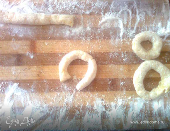 Выкладываем тесто на доску, посыпанную мукой и катаем 
"колбаски" толщиной примерно в полпальца, разрезаем колбаску на кусочки и лепим из них тоненькие бублики. Я делила тесто на удобные мне куски, а потом уже делала колбаски)
