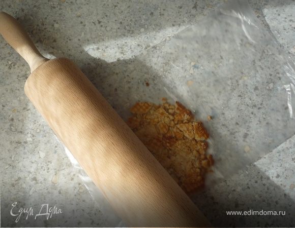 Масло растопить и остудить. Положить печенье в полиэт. пакет и при помощи скалки измельчить в крошку. 