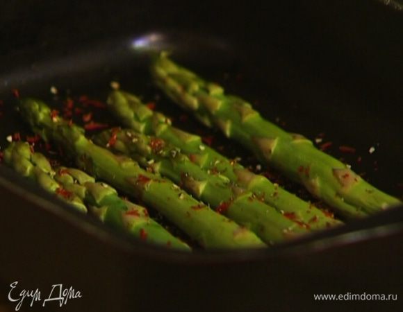 У спаржи отделить грубые части, выложить ее в небольшой глубокий противень, сбрызнуть оливковым маслом, посолить и поперчить. Потрясти противень, чтобы вся спаржа пропиталась маслом, и отправить в разогретую духовку на 5–7 минут.