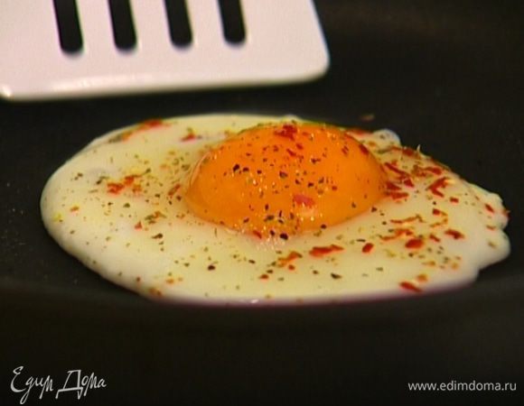 Обжаренный бекон с хлебом переложить в другую посуду, а сковороду (не добавляя масла) вернуть на огонь, разбить в нее яйцо, посолить, поперчить, посыпать измельченными сушеными помидорами и пожарить так, чтобы желток остался жидким.