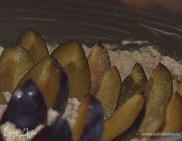 Начиная от центра, воткнуть в тесто дольки слив, наполовину погружая их в тесто (постараться разместить как можно больше слив).