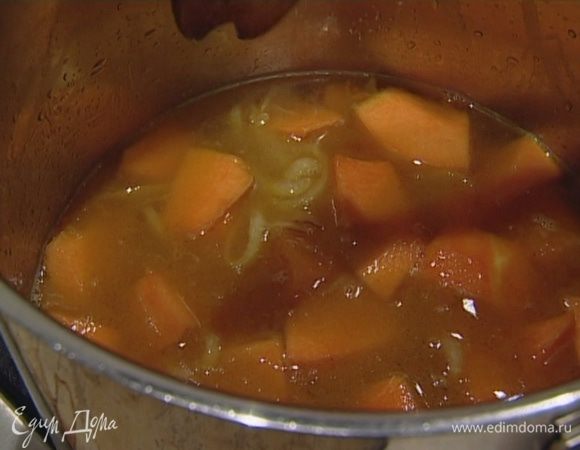 Отправить тыкву к луку, тушить около минуты, помешивая, затем залить овощным бульоном и варить до готовности тыквы, 25−30 минут.