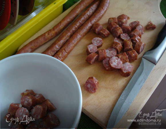 В миске взбить венчиком яйца с молоком, посолить, поперчить. Нарвать петрушку, добавить к яйцам. Нарезать колбаски (быстрее - кулинарными ножницами). Разогреть сковороду, отправить туда колбаски на пару минут. 