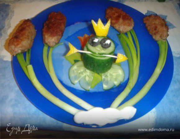 Сначала жарим обычные котлетки, только слегка продолговатые.
Затем выкладываем их с зеленым луком.
Потом из огурца, кожуры лимона и оливок делаем такую вот замечательную лягушку