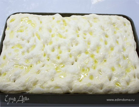 Смазать олив.маслом лоток для выпечки. Выложите тесто растягивая его руками, стараясь не порвать. Надавливая пальцами на тесто сделать ямочки. Полить небольшим количеством оливкового масла сверху,накрыть пленкой и оставить чуток подойти мин 15-20 на лотке.  