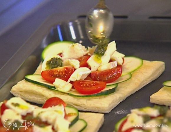 Вынуть тарталетки из духовки, выложить на них цукини, затем помидоры, сверху поместить сыр, сбрызнуть чесночной заправкой.