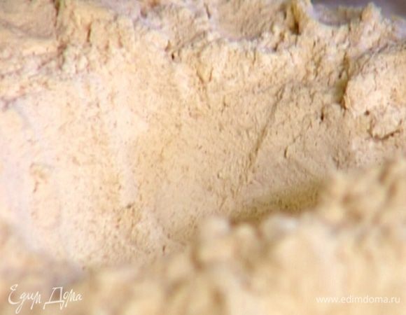 Предварительно охлажденное сливочное масло нарезать кубиками и порубить ножом вместе с мукой, а затем руками растереть так, чтобы получились крошки, и сделать из них холмик с выемкой в центре.