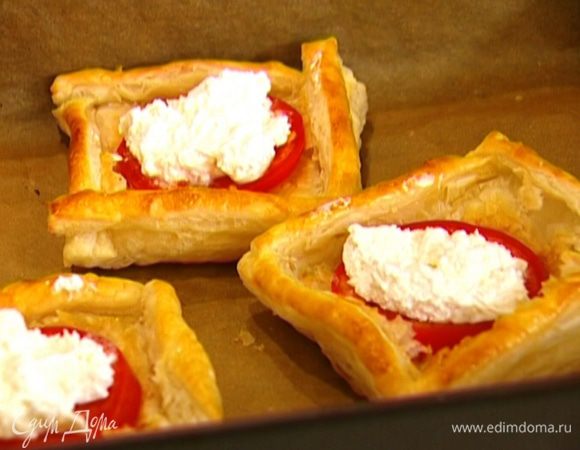 Вынуть из духовки противень с тестом, в центр каждого квадрата положить по кружку помидора, а сверху намазать козий сыр, так чтобы он полностью покрыл помидор.