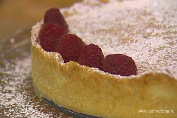 Открыть замок формы и дать пирогу слегка остыть, затем присыпать сахарной пудрой и украсить всю поверхность ягодами малины.