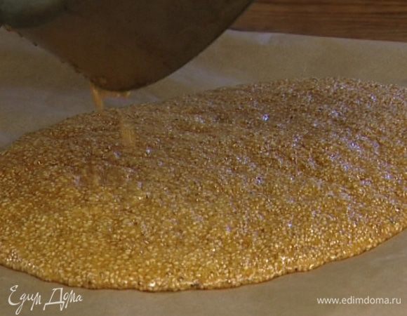 Перевернуть противень вверх дном, постелить на него бумагу для выпечки и вылить на бумагу карамель с кунжутом. Лопаткой распределить так, чтобы получился тонкий пласт, и оставить застывать.