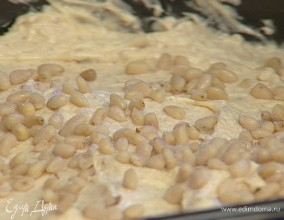 Смазать форму для кекса оставшимся сливочным маслом и выложить в нее тесто, сверху посыпать солеными кедровыми орехами.