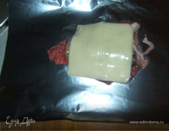 Мясо, каждый кусок, положить на лист фольги и разложить сверху грибную начинку, положить поверх грибов ломтики сыра, 