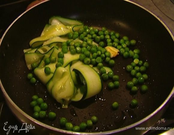 Выложить в сковороду полоски цукини, размороженный зеленый горошек и слегка прогреть. 