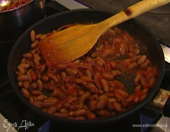 Когда соус немного уварится, выложить в сковороду отваренную фасоль, посолить, поперчить и, постоянно помешивая, обжаривать несколько минут. 