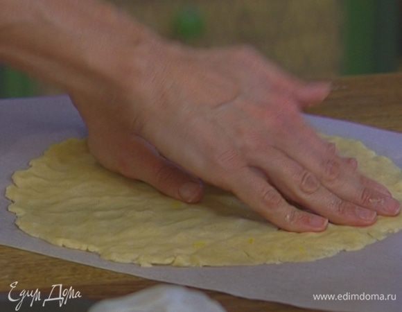 Нарисовать на листе бумаги для выпечки круг диаметром чуть больше разъемной формы и равномерно распределить в этом круге оставшееся тесто, чтобы получилась «крышечка» для пирога. Отправить форму и бумагу с тестом на 20−30 минут в холодильник.