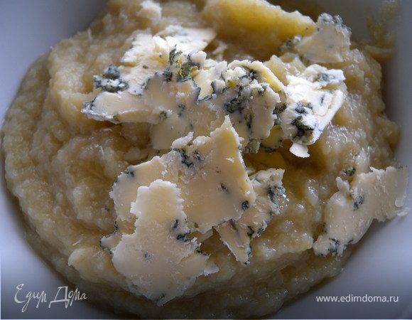 Измельчить все погружным блендером. Добавить половину сыра и перемешать. Разлить по тарелкам. Покрошить сверху оставшийся сыр и посыпать  измельченной зеленью чеснока. 