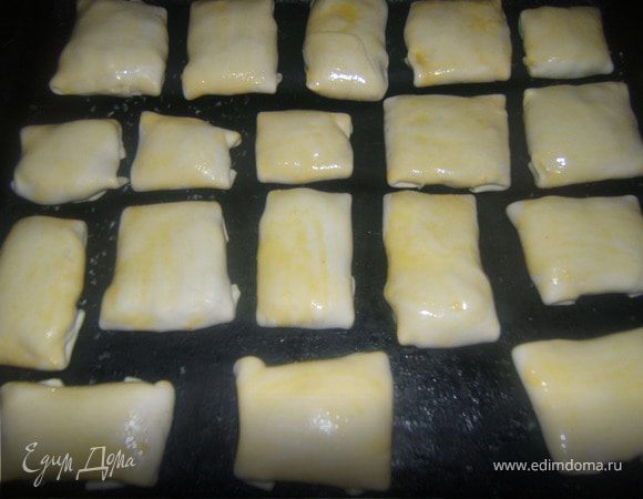 Лепим конвертики смазываем яйцом и выкладываем на смазанный маргарином противень.