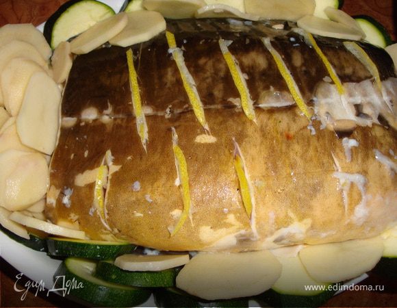 Подготовленную (почищенную, выпотрошенную, пормытую и обсушенную) рыбу немного посолить, посыпать перцем, по всей тушке сделать косые надрезы. Половинку лимона порезать полукружочками. Нашпиговать ими рыбу. Смазать форму оливковым маслом и положить туда рыбу.