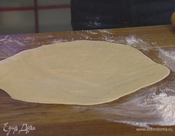 Подошедшее тесто обмять и раскатать из него на присыпанной мукой рабочей поверхности тонкий круг.