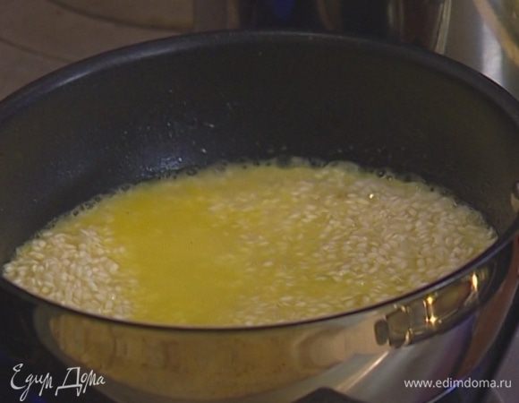 Всыпать в сковороду рис, помешивая, обжаривать пару минут, затем влить белое вино и дать ему немного выпариться. 