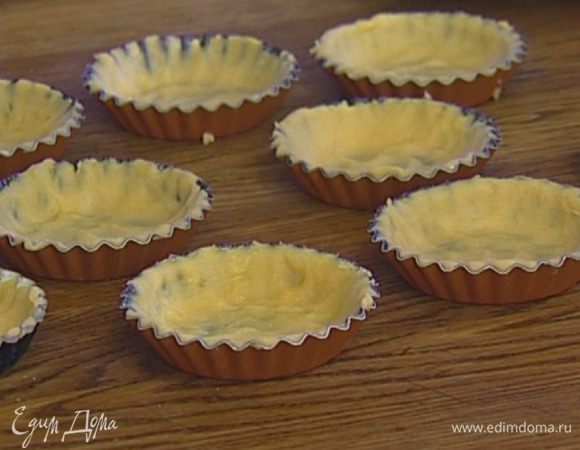 Формочки для тарталеток смазать сливочным маслом, выложить в них тесто и, прижимая пальцами, распределить его по дну и стенкам.  