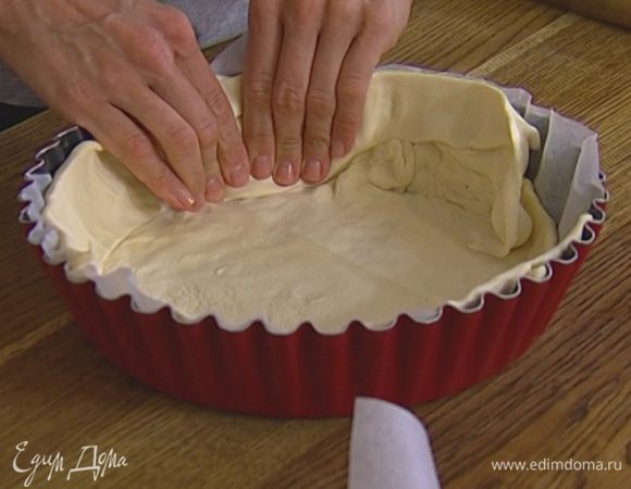 Один пласт теста слегка растянуть руками, выложить в форму и равномерно распределить его по дну и стенкам, чтобы получились бортики. Если теста окажется недостаточно, добавить второй пласт. 