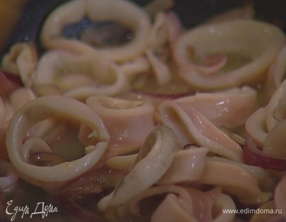 Кальмары нарезать кольцами, добавить к луку, перемешать, влить вино и дать ему выпариться. 
