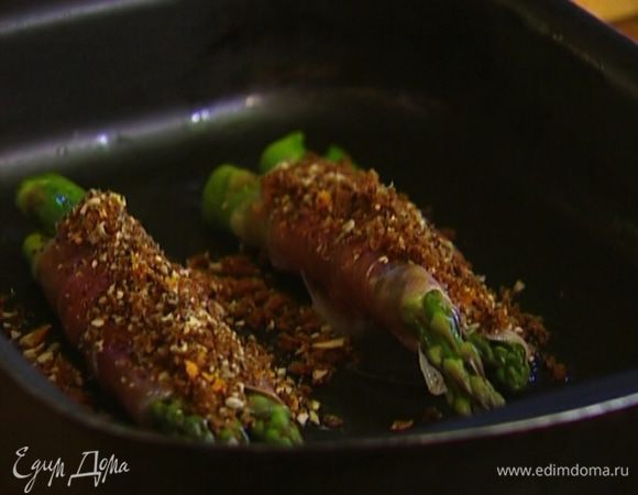 Завернуть спаржу в ломтики ветчины, вернуть в тот же противень и присыпать сухарной смесью.