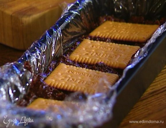 Небольшую форму выстелить пищевой пленкой, выложить шоколадную массу и украсить сверху целым печеньем.