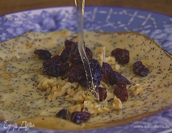 Выложить в центр каждого блина немного изюма и грецких орехов, свернуть трубочкой, полить медом.