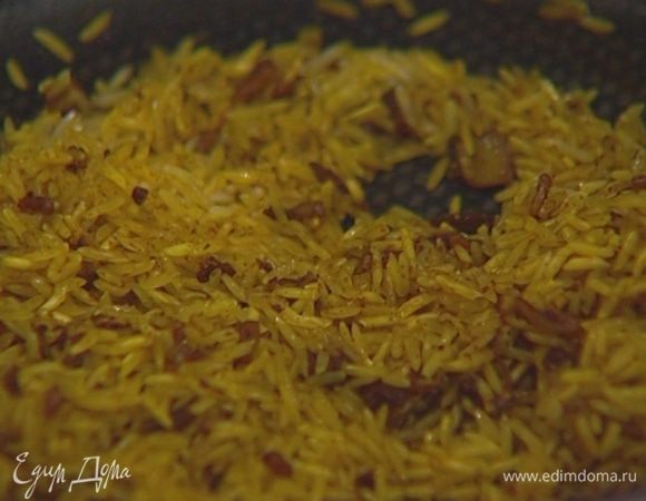 Всыпать рис, помешивая, обжаривать 1-2 минуты, затем влить горячий овощной бульон, закрыть крышкой и варить рис до готовности.