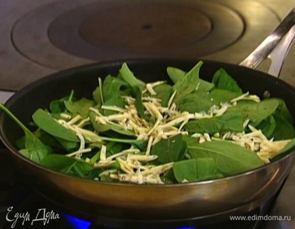 Когда края омлета схватятся, выложить шпинат, сверху посыпать натертым сыром и майораном. 