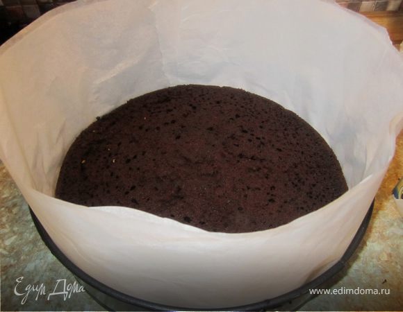 Берем разъемную форму на 30, пока немного поднимаем пергаментом. На дно ложим один корж шоколада на кипятке.