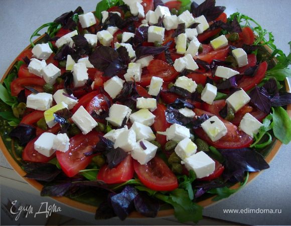 На блюдо выкладываем рукколу, затем помидоры, порезанные тонкими дольками, посыпаем их каперсами, добавляем фету кубиками. Сверху украшаем базиликом (можно чуть мелко нарезанного и целые листики),немного сбрызнуть оливковым маслом.
Салат готов!