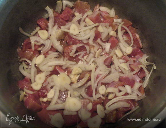 На дно кастрюли налить растительное масло. Мясо порезать на небольшие кусочки, выложить в кастрюлю, посолить, добавить перец душистый, шалфей, майоран, розмарин, сверху выложить лук, порезанный кольцами и чеснок тонкими кружочками.