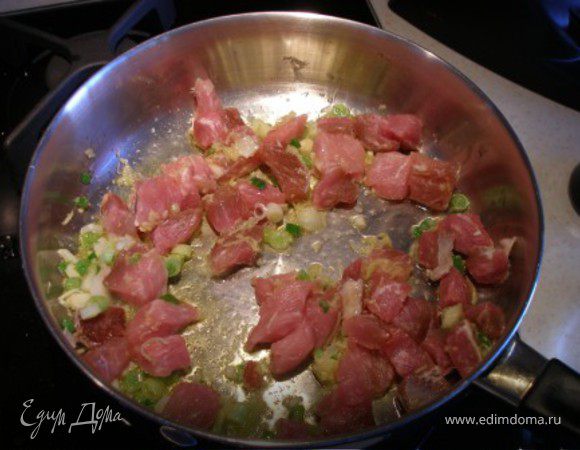 На ту же сковородку, где жарились яйца, выложить чеснок, имбирь и белую часть лука. Жарить 30 секунд. Добавить нарезанную маленькими кусочками свинину и жарить еще 5 минут. 