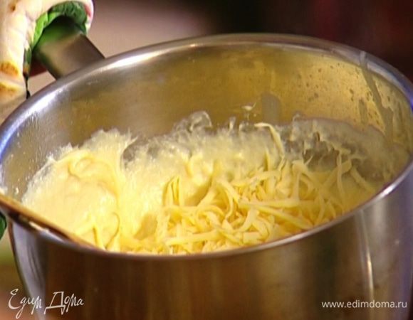 Снять кастрюлю со сливочной массой с огня, продолжая мешать, ввести желтки, затем порциями добавить сыр. 